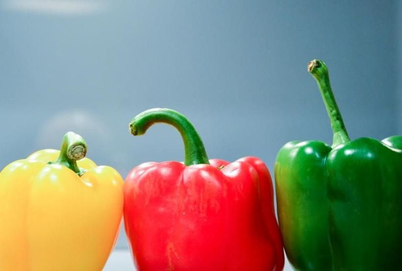 Whole red and yellow peppers, ready to roast