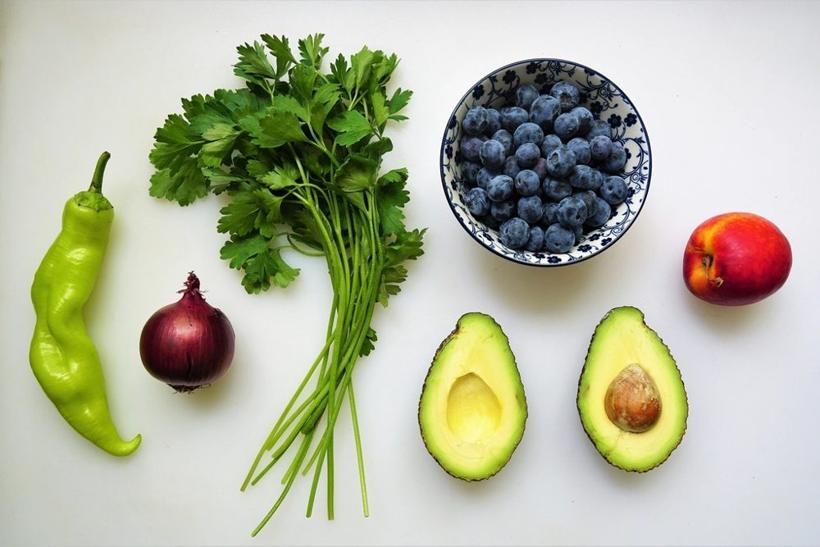 Prezzemolo, cipolla rossa, avocado e mirtilli su un piano chiaro